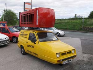 Picture of a Phoney Box being carried horizontally on the Trotter's yellow Reliant van