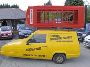 Picture of a Phoney Box being carried horizontally on the Trotter's yellow Reliant van